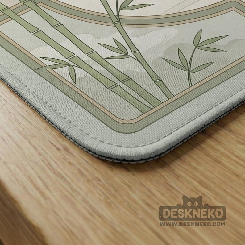 May include: A rectangular desk mat featuring a light green and cream color palette with a printed illustration of bamboo stalks and leaves. The mat has stitched edges and a small logo in the corner that reads DESKNEKO WWW.DESKNEKO.COM.