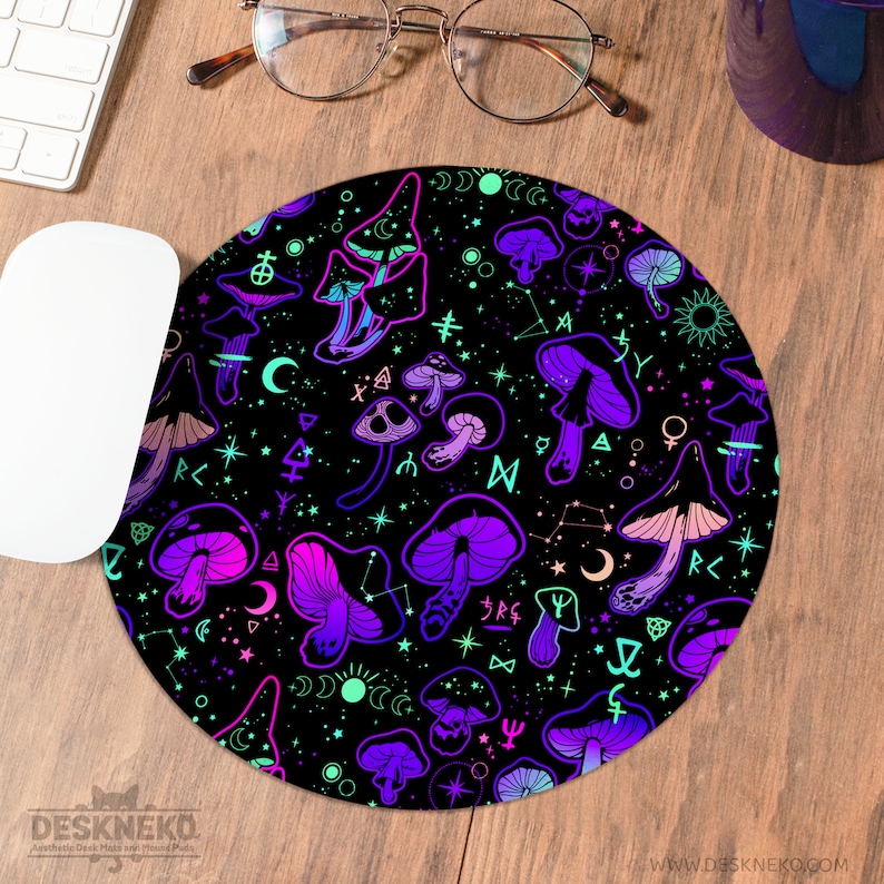 May include: Round black mousepad with a vibrant pattern of purple, pink, and teal mushrooms, stars, and celestial symbols. The mousepad has the text "DESKNEKO" and "WWW.DESKNEKO.COM" printed on it.