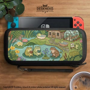 May include: Black Nintendo Switch carrying case with a whimsical illustration of frogs in a pond. The case features a black handle and a colorful design with a pond, lily pads, and a small house. A Nintendo Switch console is visible inside.