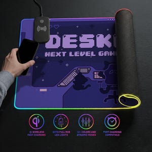 Top-down lifestyle image of an LED desk mat. The mat features a purple pixel-art gaming scene and retro interface details. One side is rolled to show the 4mm thick, textured non-slip rubber base and illuminated LED edge. A wireless charging pad is integrated near the top, with a hand holding an iPhone above it to demonstrate Qi fast charging. The mousepad border glows in along the edges. Icons below highlight wireless charging, full RGB LED lighting, 12+ color modes with dynamic effects.