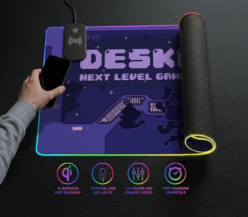 Top-down lifestyle image of an LED desk mat. The mat features a purple pixel-art gaming scene and retro interface details. One side is rolled to show the 4mm thick, textured non-slip rubber base and illuminated LED edge. A wireless charging pad is integrated near the top, with a hand holding an iPhone above it to demonstrate Qi fast charging. The mousepad border glows in along the edges. Icons below highlight wireless charging, full RGB LED lighting, 12+ color modes with dynamic effects.
