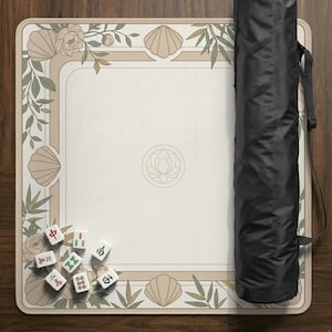 May include: A beige Mahjong game mat with a floral and seashell border design. The mat has a central lotus flower emblem and includes a black carrying case. Several Mahjong tiles are scattered on the mat.