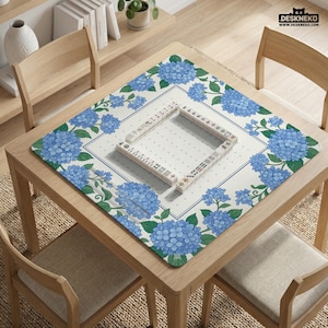 May include: A square mahjong table mat with a floral hydrangea design in blue and green. The mat is on a wooden table with a set of mahjong tiles arranged on top. The text "DESKNEKO" is visible in the top right corner.