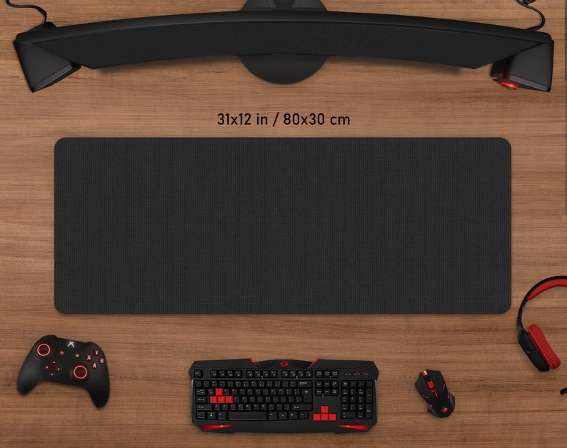 May include: A black rectangular gaming mouse pad, 31 x 12 inches (80 x 30 cm), with a textured surface. The pad is surrounded by a keyboard, mouse, controller, and headset, all in black and red.