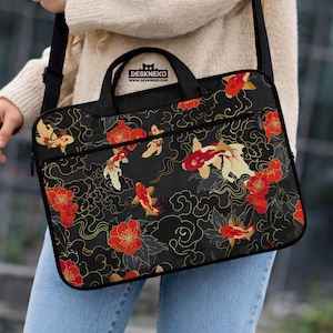 May include: Black laptop bag with a koi fish and floral pattern. The bag features red and gold accents, a top handle, and a shoulder strap. The text "DESKNEKO" is visible on the top of the bag.