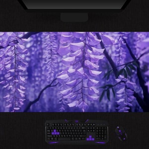 May include: A purple floral mousepad featuring a wisteria design. The image shows cascading purple flowers and green leaves against a blurred background. A keyboard, mouse, and headset are visible.