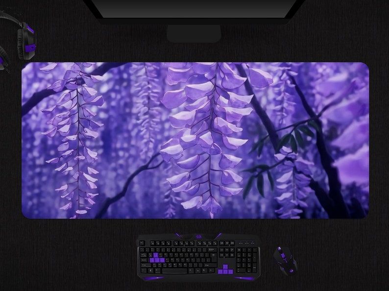 May include: A purple floral mousepad featuring a wisteria design. The image shows cascading purple flowers and green leaves against a blurred background. A keyboard, mouse, and headset are visible.