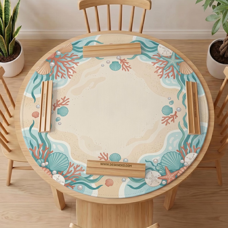 May include: A round table mat featuring a beige sandy center surrounded by a border of teal seaweed, coral, seashells, starfish, and white pearls. Four rectangular wooden card holders are placed on the mat, with one displaying the text WWW.DESKNEKO.COM.