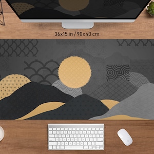 May include: A rectangular desk mat with a Japanese-inspired design. The mat features a mountain landscape with a gold sun and geometric patterns in shades of black, gray, and gold. It measures 36x15 inches.