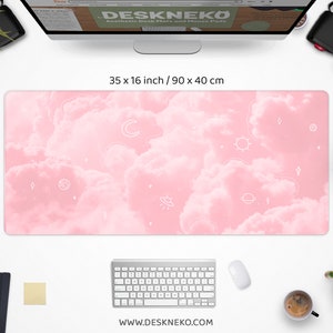 May include: Aesthetic desk mat with a pink cloud design and white celestial illustrations. The mat measures 35 x 16 inches. The website address www.deskneko.com is printed at the bottom. A keyboard, mouse, and other office supplies surround the mat.