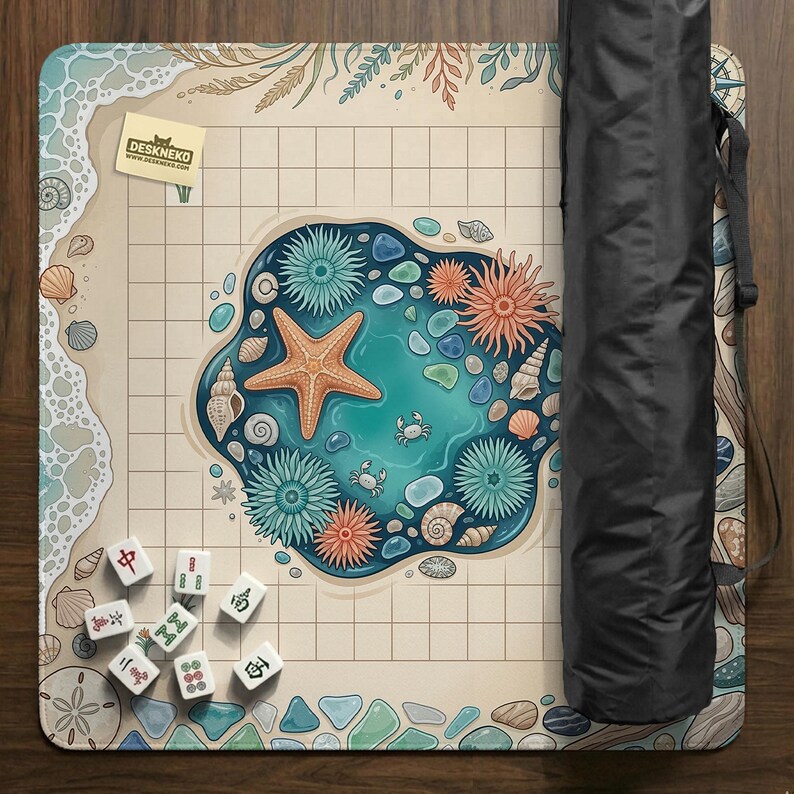 May include: A beige and blue play mat with a beach-themed design, featuring a starfish, seashells, and a small pond. The mat includes a grid pattern and a black carrying case. Mahjong tiles are scattered on the mat.