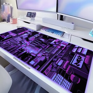K&ouml;nnte beinhalten: Ein rechteckiges, lila-schwarzes Pixel-Art-Mauspad mit einem Stadtlandschaftsdesign. Das Mauspads hat einen leuchtenden Rand und der Text "WWW.DESKNEKO.COM" ist unten links aufgedruckt.