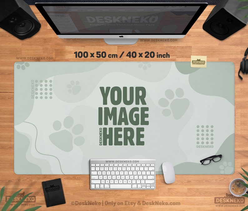 以下が含まれることがあります： 足跡と「YOUR IMAGE HERE」の文字が入った、明るい緑色のデスクマット。マットのサイズは100 x 50 cm（40 x 20インチ）です。キーボード、マウス、メガネが机の上にあります。「DeskNeko」のブランド名が見えます。