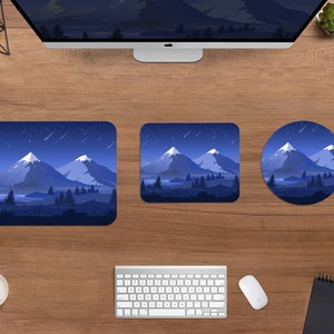 May include: A desktop setup featuring a computer monitor, keyboard, and mouse, with a square, rectangular, and round mousepad. Each mousepad displays a mountain landscape under a starry night sky, with shades of blue and white.