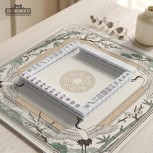 May include: A white Mahjong set arranged on a cream-colored mat with a crane and floral design. The tiles are white with red and black markings. The mat has a circular pattern in the center and the text "DESKNEKO" and "www.deskneko.com" in the upper left corner.