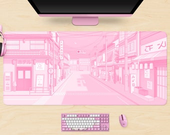 Könnte beinhalten: Rosa Schreibtischunterlage mit einer Illustration einer japanischen Straßenszene. Das Design umfasst Gebäude, Straßenlaternen und eine Straße. Eine rosa Tastatur, Maus und Monitor sind ebenfalls sichtbar.