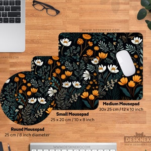 May include: A desktop setup featuring three mousepads with a floral design. The round mousepad is 8 inches in diameter, the small mousepad is 10 x 8 inches, and the medium mousepad is 12 x 10 inches. The design includes white, orange, and green flowers on a black background.