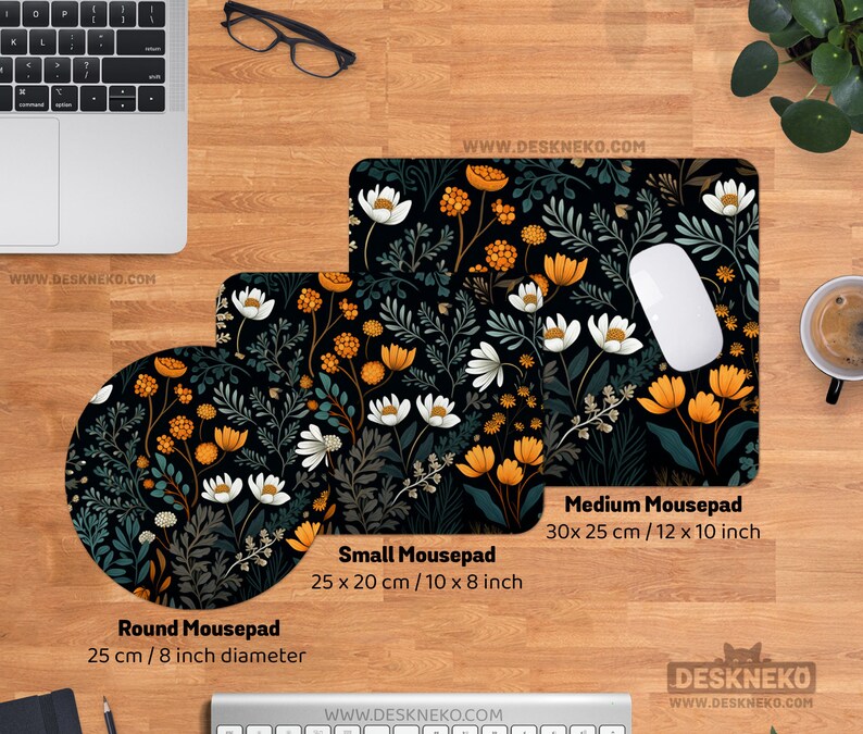 May include: A desktop setup featuring three mousepads with a floral design. The round mousepad is 8 inches in diameter, the small mousepad is 10 x 8 inches, and the medium mousepad is 12 x 10 inches. The design includes white, orange, and green flowers on a black background.