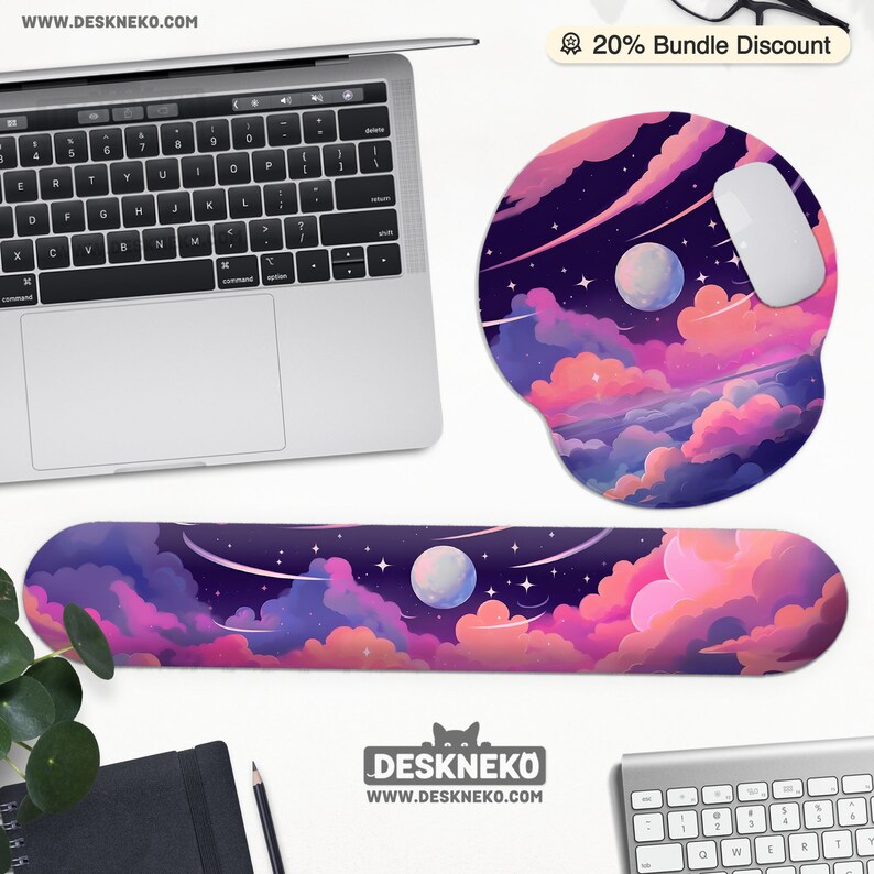 Pu&ograve; includere: Un'impostazione del computer con un laptop, un mouse e un poggiapolsi e un tappetino per mouse abbinati. Gli accessori presentano un design vibrante di un cielo notturno con pianeti, nuvole e stelle. L'indirizzo del sito web "WWW.DESKNEKO.COM" &egrave; visibile.