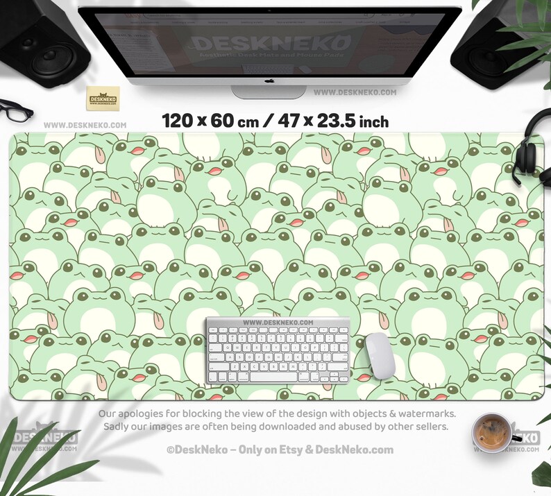 May include: A large desk mat featuring a repeating pattern of cartoon frogs in shades of green and cream. The mat measures 47 x 23.5 inches and includes a keyboard and mouse. The text "DESKNEKO" and "WWW.DESKNEKO.COM" are visible.