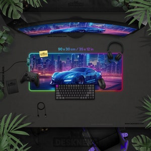 May include: A gaming setup featuring a curved monitor, a large mousepad (35 x 12 in) with a car graphic, a keyboard, mouse, and headphones. A game controller and a small notebook are also present. The setup is on a dark surface with a city skyline background.