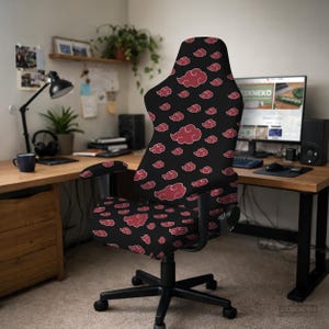 May include: Black office chair with a red cloud pattern. The chair has a high back, armrests, and a five-star base with wheels. The red clouds are scattered across the black fabric, creating a striking contrast. The chair is in a home office setting.