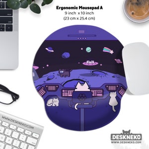 Könnte beinhalten: Ergonomisches Mauspad mit Weltraum-Design. Das lila Mauspad zeigt eine Katze, die ein Raumschiff steuert, mit Planeten, Sternen und UFOs im Hintergrund. Es misst 23 cm x 25,4 cm.