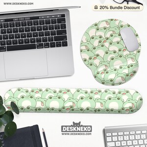 May include: A computer desk setup featuring a laptop, mouse, and keyboard. The set includes a green frog-themed mousepad, wrist rest, and a white mouse. The frog design is repeated across the accessories. The website address is visible.