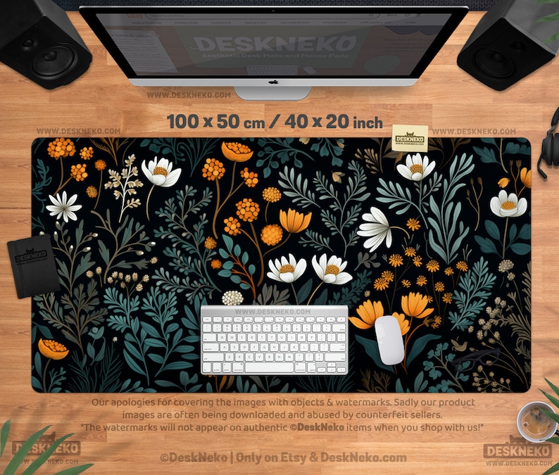 May include: A black desk mat with a floral design featuring white and orange flowers, green leaves, and stems. The mat measures 40 x 20 inches. A keyboard and mouse are on the mat.