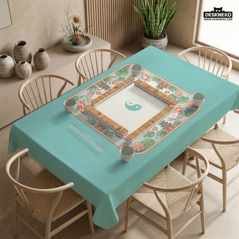 May include: A teal tablecloth with a decorative Mahjong game board featuring a Yin and Yang symbol. The board is surrounded by koi fish, lotus flowers, and traditional Asian architecture. The table is set with small bowls and chopsticks.