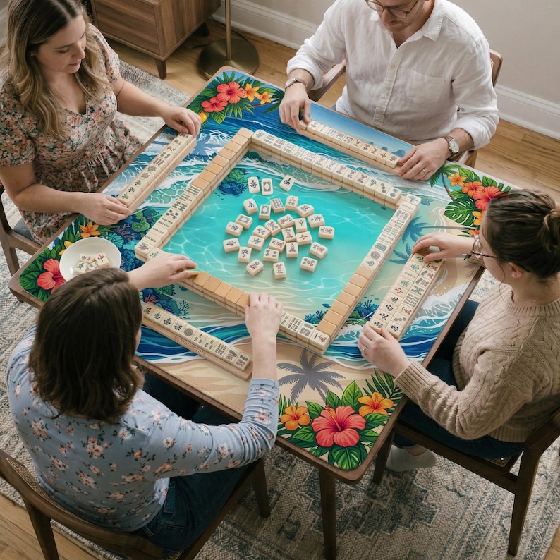 May include: A square Mahjong table with a tropical beach design, featuring a turquoise water scene and floral accents. The table is surrounded by players, with tiles and racks visible. The table is approximately 36 inches square.