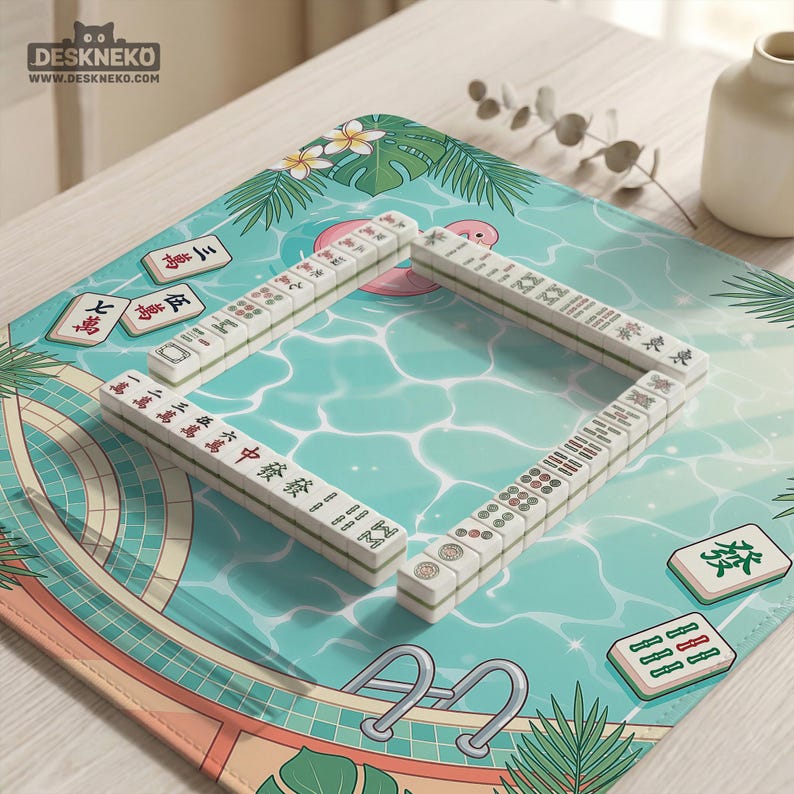 May include: A Mahjong set arranged on a pool-themed playmat. The tiles are white with black and red markings. The playmat features a pool design with palm fronds and floral accents. The logo "DESKNEKO" is visible in the top left corner.