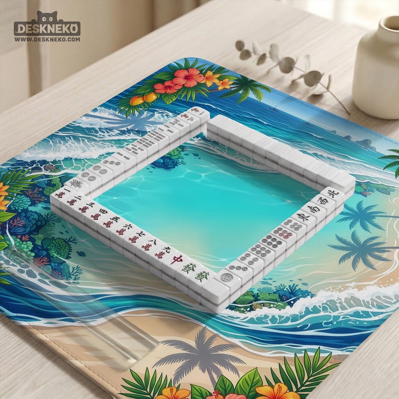May include: A Mahjong set with white tiles and red and black characters is arranged on a tropical-themed playmat. The mat features a beach scene with turquoise water, palm trees, and floral accents. The logo "DESKNEKO" is visible in the top left corner.