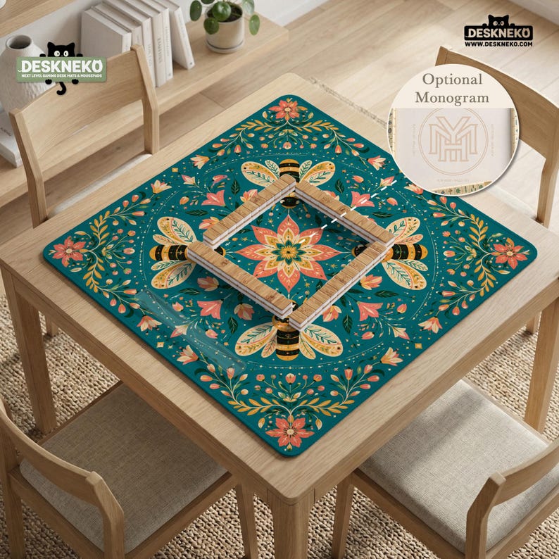 May include: A square desk mat featuring a teal background with a symmetrical pattern of bees, flowers, and foliage in shades of orange, yellow, and green. A wooden frame sits in the center, and a circular inset shows an optional monogram design.