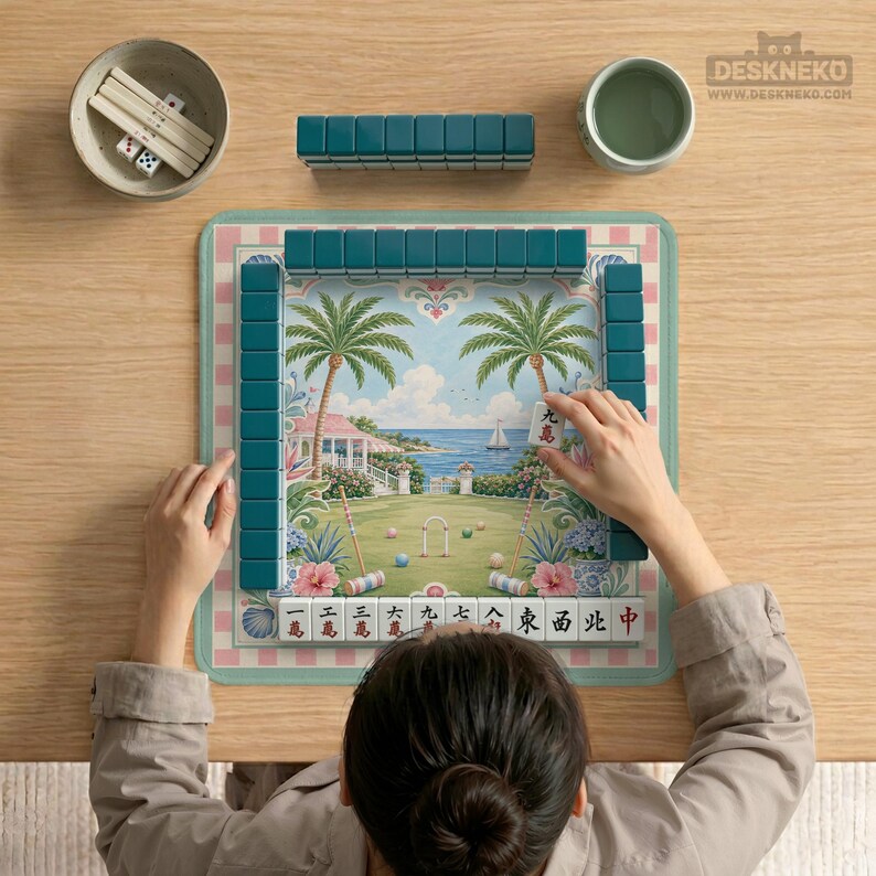 May include: A complete Mahjong set with teal tiles, dice, and a bowl. The game board features a tropical landscape with palm trees, a house, and a sailboat. The game is set on a wooden table.