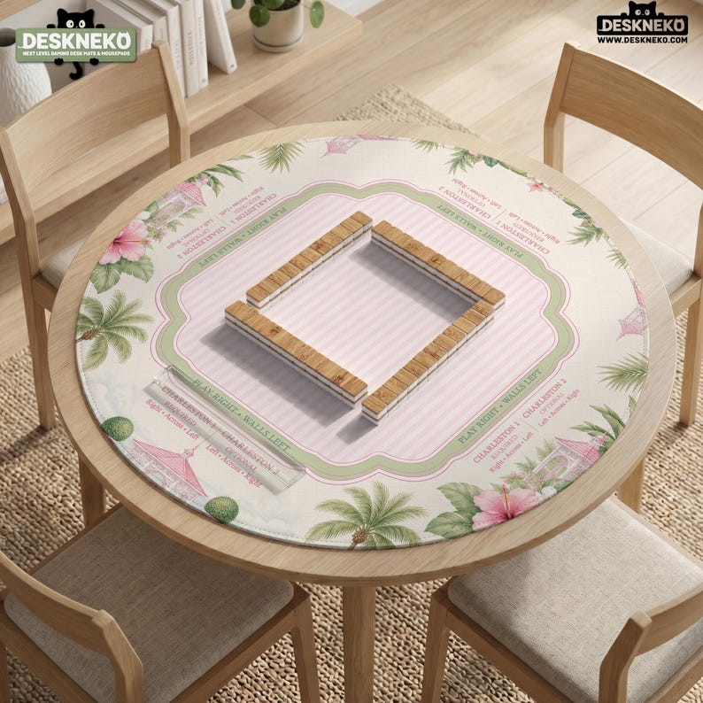 May include: A round mahjong mat featuring a light pink and white striped center with a green border, decorated with tropical palm trees, pink hibiscus flowers, and gazebos. The mat includes printed text for Charleston and wall directions.