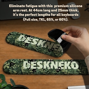 May include: A green and white silicone arm rest with the text "DESKNEKO" and a leaf pattern. The arm rest is 17.3 inches long and 1 inch thick. The image also shows a black computer mouse.