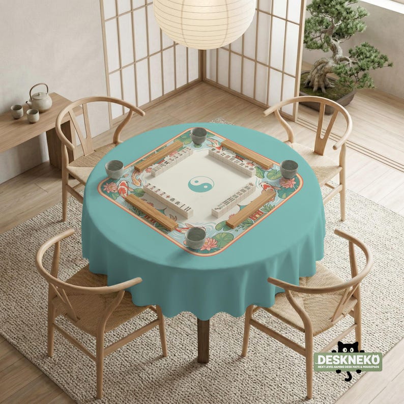 May include: A round teal tablecloth with a Mahjong game set in the center, surrounded by four wooden chairs. The Mahjong set has a white playing surface with a yin-yang symbol and is decorated with koi fish and lotus flowers.