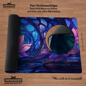 May include: A rolled-up desk mat with a stained-glass design in shades of blue, purple, and pink. The mat is made of 2mm thick neoprene rubber and cloth with a non-slip backing. The text on the mat says "DESKNEKO" and "Also works as a mousepad!"