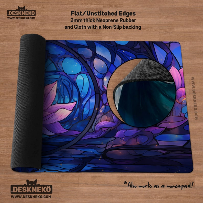 May include: A rolled-up desk mat with a stained-glass design in shades of blue, purple, and pink. The mat is made of 2mm thick neoprene rubber and cloth with a non-slip backing. The text on the mat says "DESKNEKO" and "Also works as a mousepad!"
