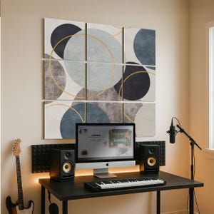 May include: A home studio setup with a computer, keyboard, and speakers on a black desk. Above, a multi-panel abstract artwork with blue, grey, and gold circles. A guitar and microphone are also visible.