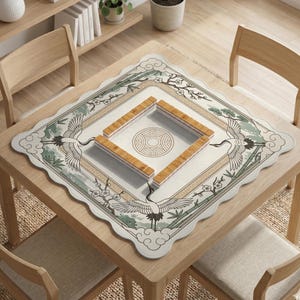 May include: A square mahjong table mat with a decorative border featuring cranes, bamboo, and floral elements. The mat is placed on a wooden table, with wooden mahjong tiles arranged in a square. The mat's design includes a central circular pattern.
