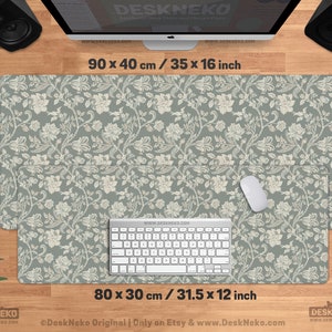 Puede incluir: Alfombrilla de escritorio con estampado floral en verde salvia y crema. La alfombrilla principal mide 90 x 40 cm, con un &aacute;rea de alfombrilla de rat&oacute;n adjunta de 80 x 30 cm. Un teclado y un rat&oacute;n est&aacute;n sobre la alfombrilla. El texto "DeskNeko" es visible.