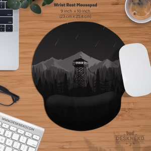 May include: Black and gray wrist rest mousepad with a forest and mountain scene. The mousepad is 9 inches by 10 inches. The design features a watchtower, trees, and mountains under a starry sky. A white mouse and keyboard are also visible.