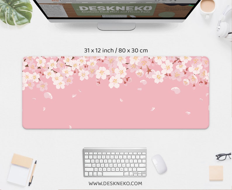 May include: Aesthetic desk mat with a pink background and a floral cherry blossom design. The mat measures 31 x 12 inches. The website address www.deskneko.com is printed at the bottom.