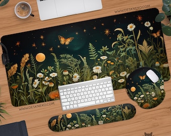 Op de afbeelding: Een bureau-opstelling met een groot rechthoekig muismat, een ronde muismat en een polssteun, allemaal met een bijpassend bloemen- en vlinderontwerp. Het ontwerp bevat madeliefjes, varens en een volle maan tegen een donkere achtergrond. De website www.deskneko.com is afgedrukt.