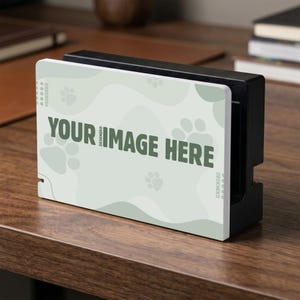 May include: A black and white electronic device with a light green and white cover. The cover features the text "YOUR IMAGE HERE" in dark green, along with paw prints and the word "DESKNEKO".