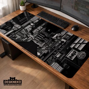 May include: Black and white desk mat featuring a pixelated cityscape with Japanese text and the word "TOKYO". The mat has a rectangular shape and the text "DESKNEKO" is printed on the bottom.