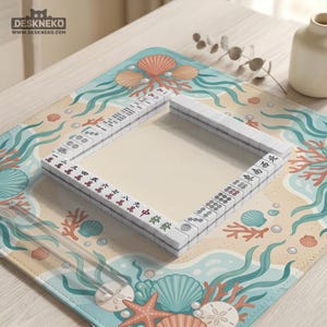 May include: A square mahjong tile set arranged in a hollow square formation on a desk mat featuring a light blue and beige ocean-themed pattern with seashells, coral, and seaweed. The white tiles display black and red Chinese characters and symbols.