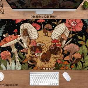 Może przedstawiać: Duża podkładka pod biurko z motywem czaszki i grzyb&oacute;w. Mata ma wymiary 100x50 cm i zawiera szczeg&oacute;łową ilustrację z czarnym tłem, r&oacute;żnymi grzybami i elementem kwiatowym. Tekst "DESKNEKO" znajduje się na dole.